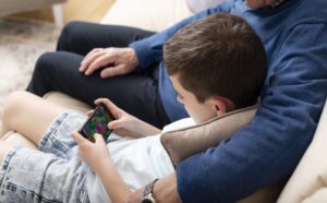 Мальчик играет в игру на телефоне